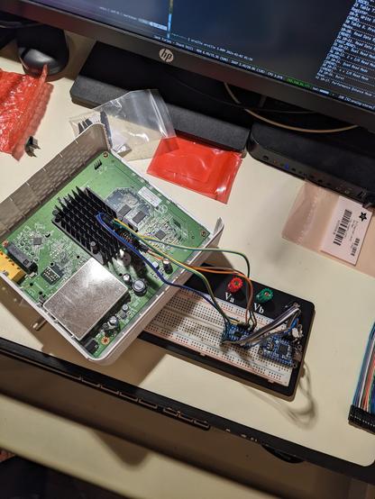Hitron-brand cable modem with plastic cover removed. Clip connected to SPI flash, with wires trailing to a bi-directional level shifter and an FT232H breakout board