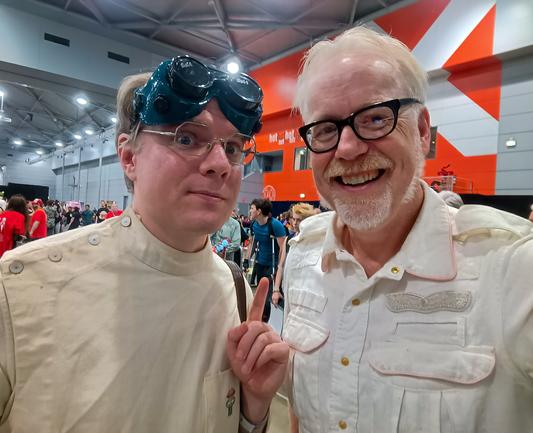 A man dressed as Dr Horrible, an evil mad scientist with a white medical smock, standing next to Adam Savage