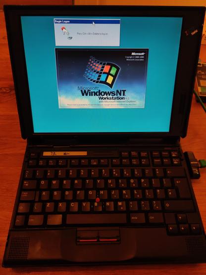 A 45° downward angle photo taken from eye-level of the Thinkpad with the screen open and the Windows NT4 login screen prompting me to "Press Ctrl + Alt + Delete to log on".

The computer screen has correct colour balance; the laptop and background has an intense orange cast.