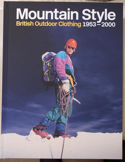 A hardback book titled Mountain Style: British Outdoor Clothing 1953 - 2000. The cover shows a mountaineer in brightly coloured gear, a red helmet, sunglasses, roped up and in snow.