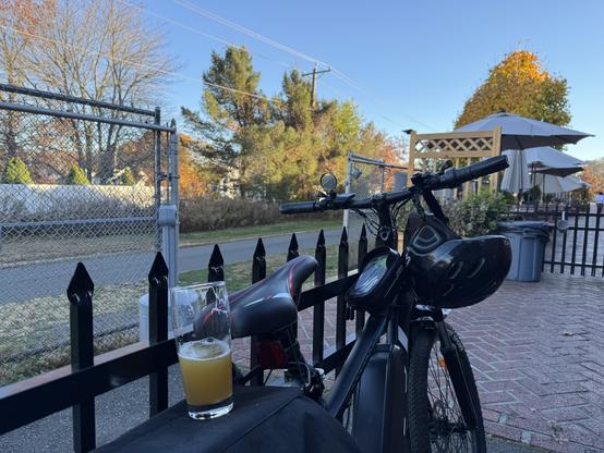 The view from a picnic table shows a New England IPA resting on the back of a parked bicycle. Autumn foliage flanks the paved trail that runs through the background. Once that beer is gone, Iβll hop back on the bike and keep riding.