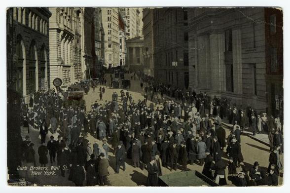 The image depicts a bustling urban scene from the early 20th century, likely in New York City. It captures a crowded street with numerous individuals engaged in various activities such as walking or gathering around what seems to be a curb where brokers are stationed on Wall Street. The clothing suggests men dressed for business; many wear suits and hats indicative of that era's fashion among professionals.

In the background, classical architecture is visible, including tall buildings with detailed facades, large windows, and ornate designs typical of late 19th-century to early 20th-century commercial structures in urban areas. The street appears busy yet orderly, with a few individuals seated on steps leading up to one building.

A horse-drawn carriage can be seen at the far end, suggesting that this mode of transport was common during the time depicted. Shadows cast by buildings indicate bright sunlight and possibly midday or early afternoon timing for the photograph's exposure.

The sepia-toned quality suggests it is a historical image rather than a recent one. There are no explicit signs indicating modern technology or contemporary elements within view, reinforcing its vintage nature.

This visual narrative provides insight into daily life on Wall Street during that period and captures the bustling energy of financial district activity in New York City's past.