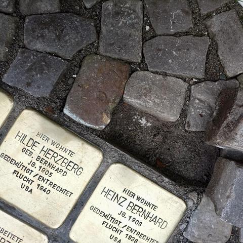 Das Bild zeigt einen Abschnitt des Kopfsteinpflasters mit zwei Stolpersteinen und einem Loch daneben.