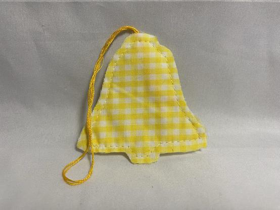 A yellow fabric bell-shaped ornament made of checked material, featuring a hanging string.