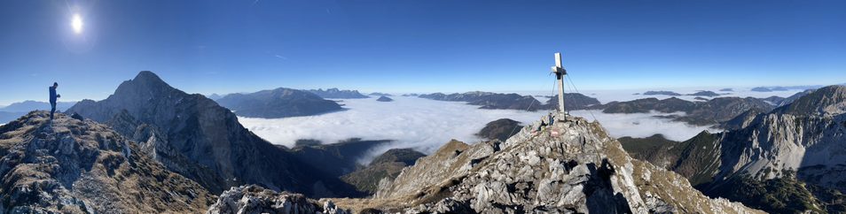 Bergpanorama mit Blick aufs Nebelmeer und einem Gipfelkreuz rechts