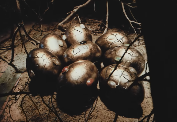 8 bronze eggs in the process of cracking. most of them have two visible gemstones on them.