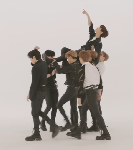 The original 7-person minhandling. 7 members of skz hold Seungmin aloft while he lies back and gestures upwards.