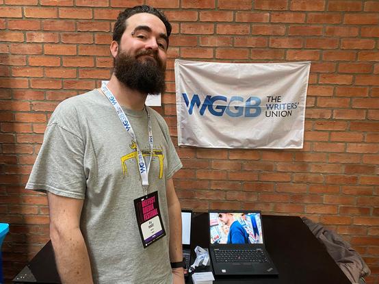 Photo of WGGB Northern Ireland rep PJ Hart in front of the WGGB stand at Belfast Media Festival