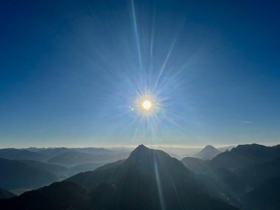 Blauer Himmel mit Sonnenstrahlen und Bergpanorama