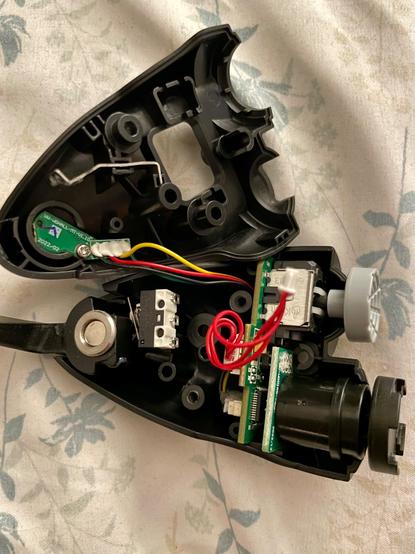 Interior of the Winwing “Shaker” module showing various sensors, connectors, and chip boards. An isolated white and black electronic switch is glued to the plastic housing to provide a tactile, audible “click” to the second additional trigger the module provides.