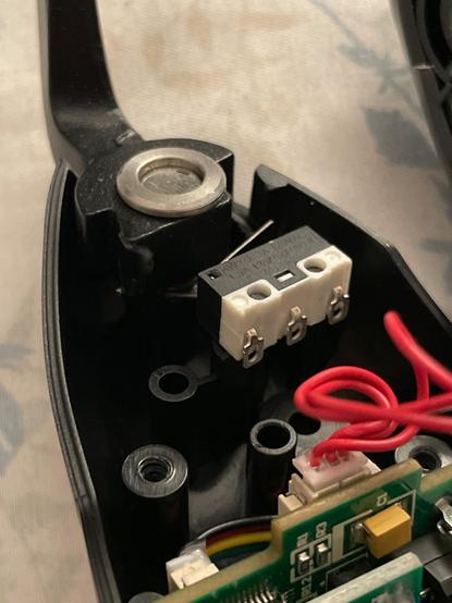 Interior of the Winwing “Shaker” module showing various sensors, connectors, and chip boards. An isolated white and black electronic switch is glued to the plastic housing to provide a tactile, audible “click” to the second additional trigger the module provides.