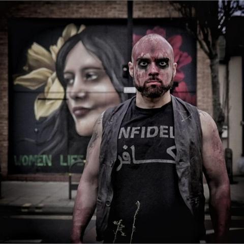 Shayan (Trivax) with a mural of Mahsa Amini