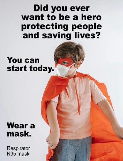 A young child dressed as a superhero in a red cape and mask is wearing an N95 respirator mask. The image features bold text encouraging people to wear masks to protect others and become heroes.