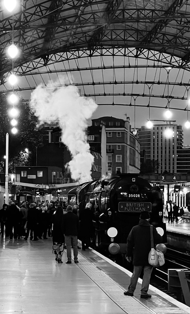 Old Pullman engine in station with people on platform and smoke rising into sky