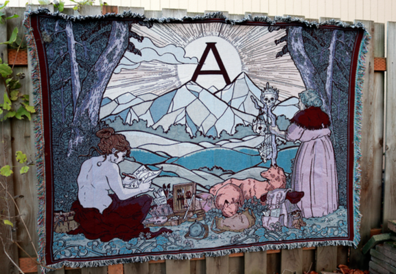 an image of an oversized tapestry hanging on a fence. It shows four figures overlooking a valley in which a circle a sun rises over a mountain. The figure on the left leans over and paints the scene. They are surrounded by travelling art boxes. The figure on the right leans on a staff which has king skulls hanging from it. At their feet two foxes get into their travelling sacks.