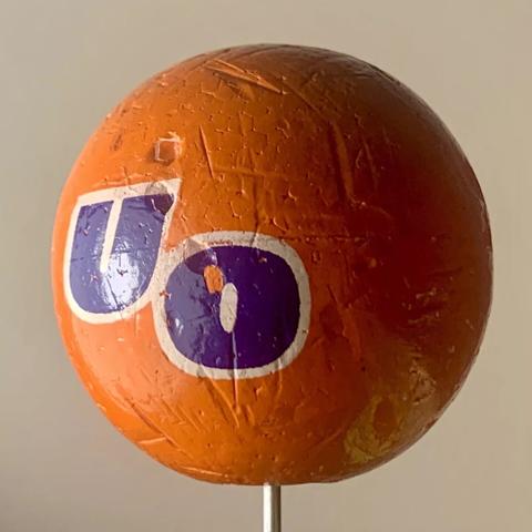 A photo of a vintage orange antenna/aerial topper with the Urge Overkill "UO" logo emblazoned in purple & white across the front.