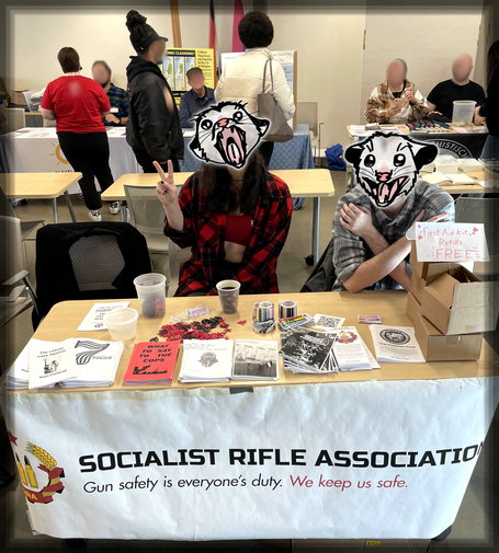 The SRA table at the Building Bridges Summit. Photo of comrades with possums for faces