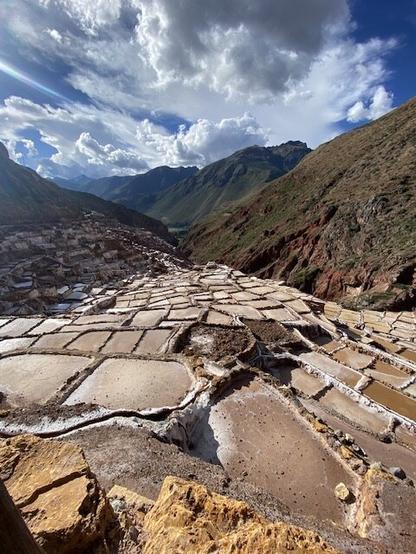 Salt pools in a mountain valley under high clouds at Maras, Peru
