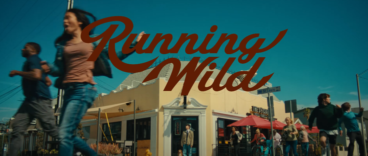 A screenshot from Jin's Running Wild MV, with people running down a street in chaos mode, while Jin and his pupper watch.