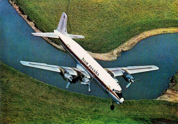 View is a birds-eye and we see the plane coming in for a landing over water and grass.