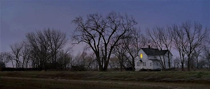 A view of a small white farmhouse in a rural area