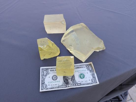 4  pieces of glass. 2 are very heavy and bright yellow. They are made from 70% lead oxide and a small amount of cerium to keep the radiation from browning them.  They were used for the interior windows . The other 2 are a lighter color and have less lead oxide in them. They were used in the exterior viewing windows since the 70% lead oxide windows were very soft and scratched easily. All are laying on a dollar bill to show size. The heavy ones together re about 1/2 the bill and the other 2 would cover most of the bill.