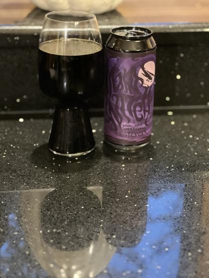 A stout glass full of pitch black beer. The pint can is to the right, its purple label adorned with “Nigh Witch” in wiggly black letters. a small plane flies in front of a pink full moon in the upper right