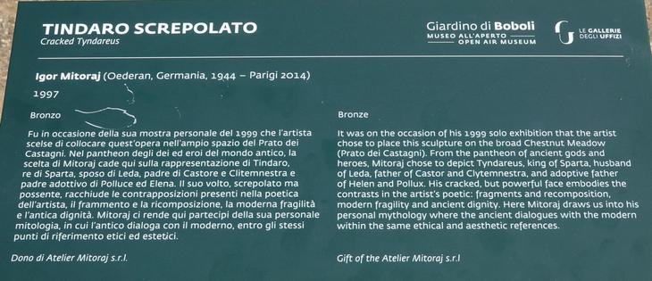 Description of the sculpture in English:

"Cracked Tyndareus
Igor Mitoraj (1944 - 2014)
Bronze

It was on the occasion of his 1999 solo exhibition that the artist chose to place this sculpture on the broad Chestnut Meadow (Prato dei Castagni). From the pantheon of ancient gods and heroes, Mitoraj chose to depict Tyndareus, king of Sparta, husband of Leda, father of Castor and Clytemnestra, and adoptive father of Helen and Pollux. His cracked, but powerful face embodies the contrasts in the artist’s poetic: fragments and recomposition, modern fragility and ancient dignity. Here Mitoraj draws us into his personal mythology where the ancient dialogues with the modern within the same ethical and aesthetic references.

Gift of the Atelier Mitoraj s.r.l"