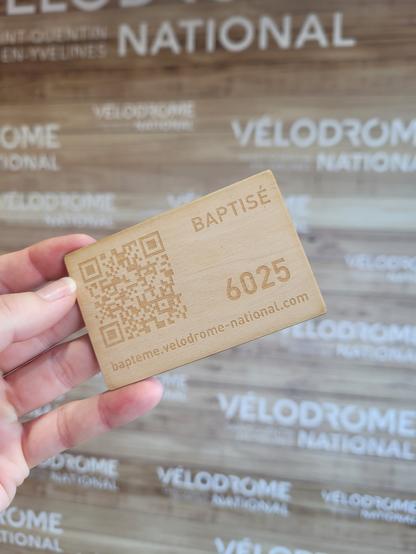Ma main qui tient une petite carte en bois indiquant "baptisé" et un QRcode