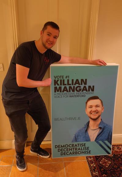 A photo of Killian smiling with his posters