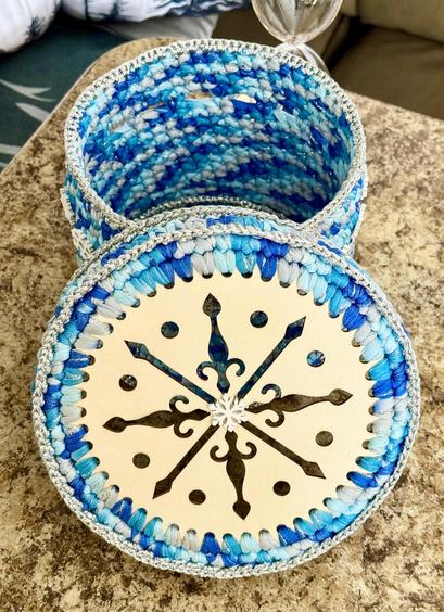 Blue and Silver hand crocheted basket with laser carved top! Top and bottom are wooden circles and the body of the basket is made of heavily starched t-shirt yarn! The silver edging is actually baking twine crocheted in to accent the basket!