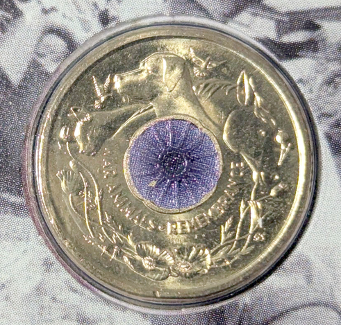 Australia 2024 Animals in War NCLT coin.  From: https://en.numista.com/catalogue/pieces435961.html

Reverse
A purple poppy centre surrounded by A Cat, Dog, Horse & Doves. All set above Australian Flora.

Script: Latin

Lettering:
WAR ANIMALS REMEMBRANCE
C
BS

Designer: Bronwyn Scott