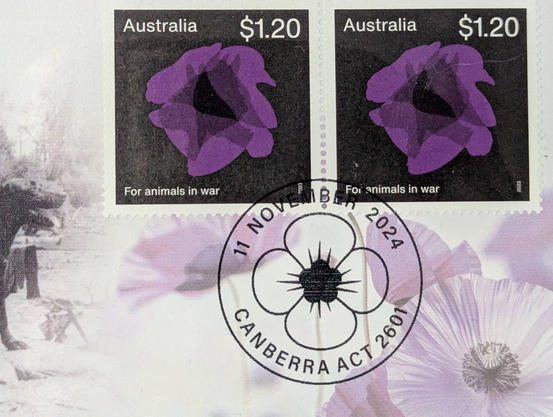 Close up of the stamps.  Two stamps with black backgrounds, Australia top left, $1.20 top right, "For animals in war" lower left and a purple poppy made up of animal heads central.  Cancellation mark is 11 November 2024, Canberra ACT 2601.