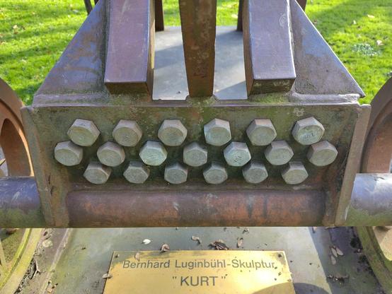 Schild unter der Skulptur mit der Aufschrift:
Bernhard Luginbühl-Skulptur
"Kurt"