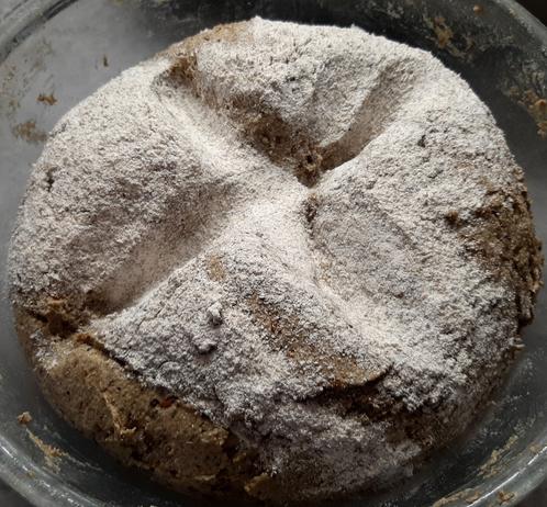 A rye bread dough at the beginning of its rise in a bowl. With a cross pressed on top with the side of the palm, as is tradition.