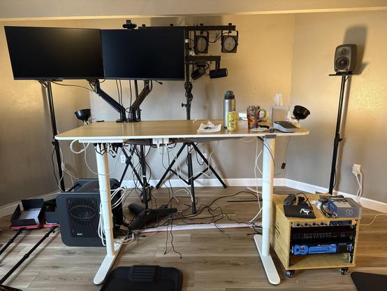A picture of a desk with two monitors and wires everywhere
