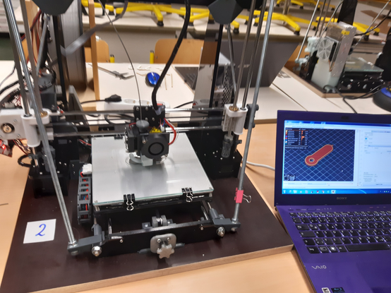 3D-Drucker und ein Laptop mit geöffnetem Slicer.