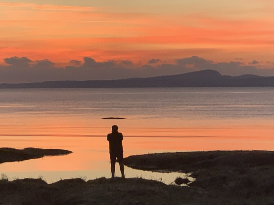 Pinky red sunset with someone silhouetted in the foreground.