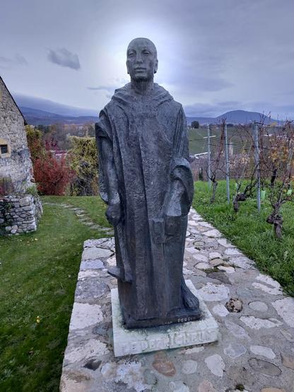 Eine eiserne Statue eines Mannes. Die Sonne ist direkt hinter seinem Kopf.