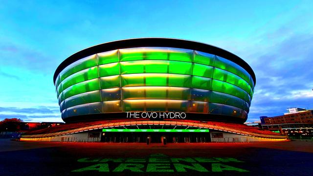 A space-ship like building lit up green at night.