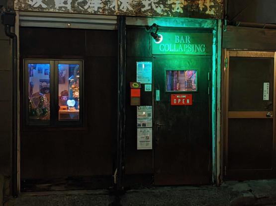 Bar Collapsing in block letters illuminated by green light above a door