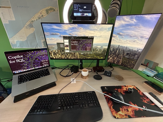 Picture of a standing desk with a laptop, multiple screens, ringlight and prompter showing a PowerPoint presentation