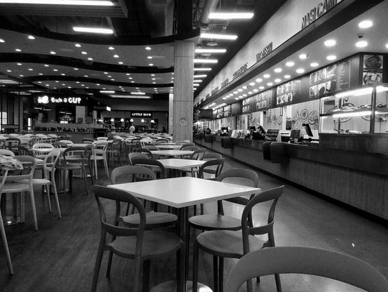 an food court at Lotus's in Penang with the food stalls getting ready for business. the empty tables and chairs stretch from the foreground to the background.