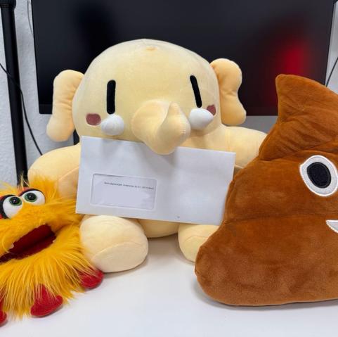Drei Stofftiere tragen einen Brief, von links nach rechts eine Handpuppe, die wie ein Virus aussieht, das Mastodon-Mammut als Stofftier und das Kacke-Emoji, ebenfalls als Kissen.