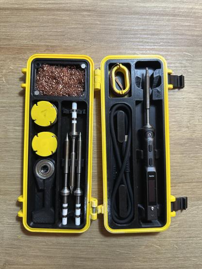 Bild 1: Geöffnete gelbe Aufbewahrungsbox mit einem Lötwerkzeug-Set (TS101), bestehend aus Lötkolben, Aufsätzen, Reinigungsschwammtopf und Kabeln.