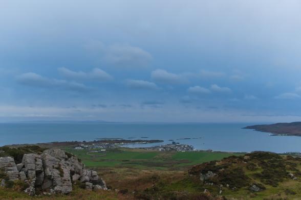 a village round a bay seen from a small hill with a dark blue sky