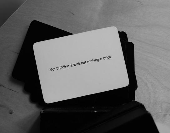 An oblique strategies card that says "Not building a wall but making a brick"
