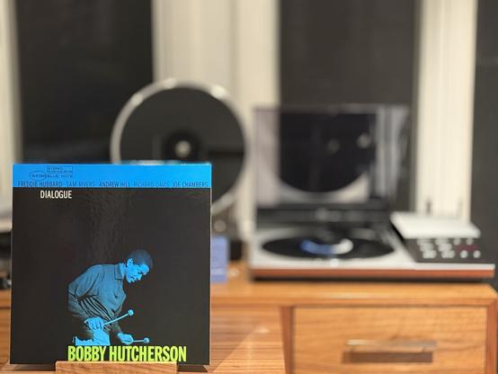 Bobby Hutcherson - Dialogue LP cover.

A blue-tinted black and white photo of Hutcherson playing the vibes. A blue strip on top has the other band members, while the title is upper left (below) in white. At the bottom, where the vibraphone would be, is Bobby’s name in yellow.