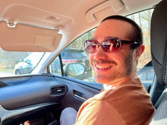 Wesley in the front passenger seat with slightly too small sun glasses. Smiling! Sunshine!