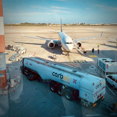 The image shows a Ryanair passenger jet on the airport tarmac, with a Carboil fuel tanker in the foreground. This suggests the image is capturing the refueling or servicing of the Ryanair aircraft at the airport.